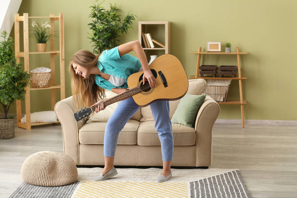 Gyönyörű fiatal nő gitározik és énekel otthon - Fotó, kép