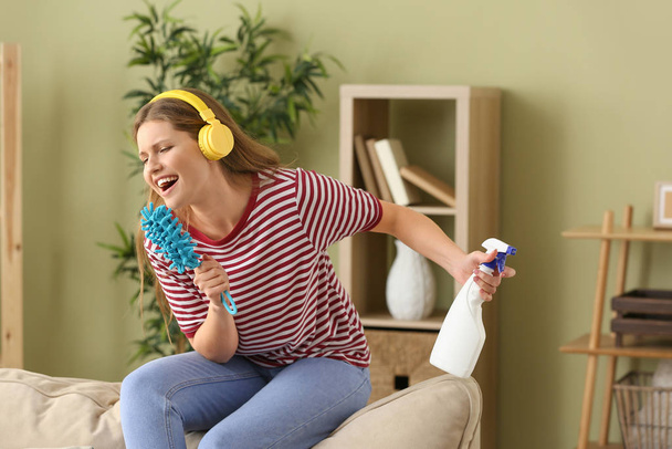 Beautiful young woman singing while cleaning her flat - Foto, imagen
