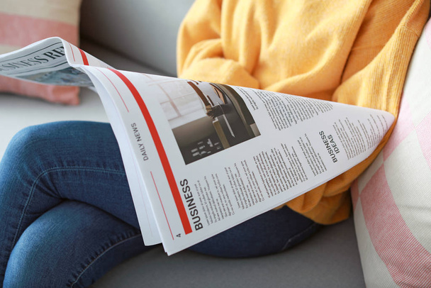 Молодая женщина читает газету дома, крупным планом
 - Фото, изображение