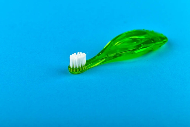 Green childrens toothbrush. on a blue background. Place for an inscription. Toothbrushing a child. - Photo, Image