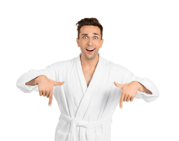 Izgatott férfi fürdőköpenyben mutat valamit a fehér háttér - Fotó, kép