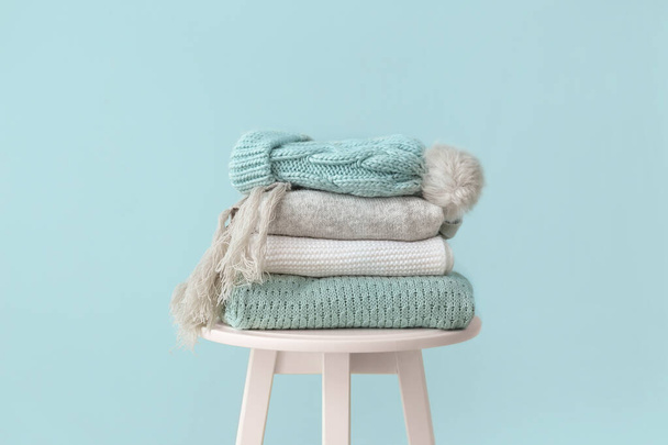Набор теплой зимней одежды на столе на цветном фоне
 - Фото, изображение