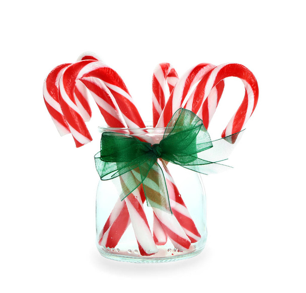 Frasco de vidro com bastões de doces de Natal no fundo branco
 - Foto, Imagem