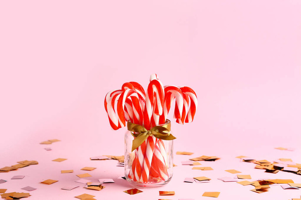 Tarro de vidrio con bastones de caramelo de Navidad sobre fondo de color
 - Foto, imagen