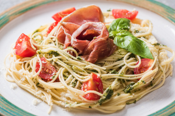 close up view of cooked Pappardelle with tomatoes, basil and prosciutto - Foto, imagen