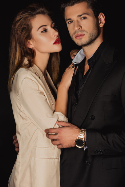 attractive woman hugging handsome man in suit isolated on black - Fotoğraf, Görsel