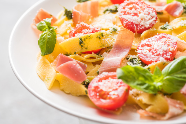 close up view of delicious Pappardelle with tomatoes, Parmesan, pesto sauce, basil and prosciutto - Foto, immagini