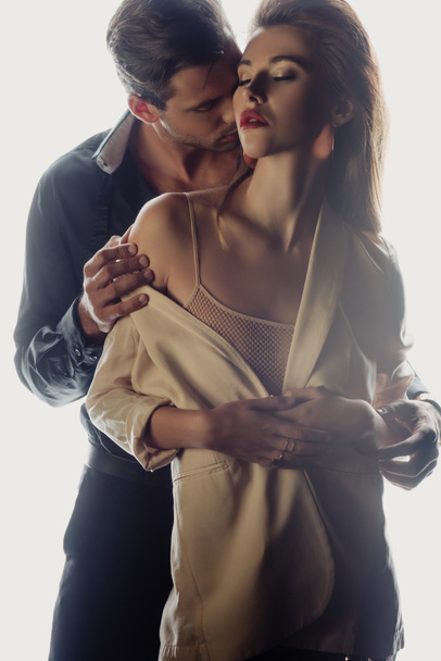 knappe man knuffelen en kussen aantrekkelijke vrouw geïsoleerd op wit - Foto, afbeelding