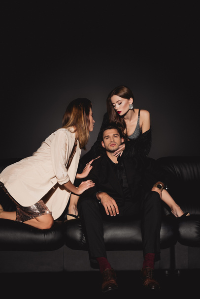 attractive and stylish women hugging handsome man on black background  - Fotografie, Obrázek