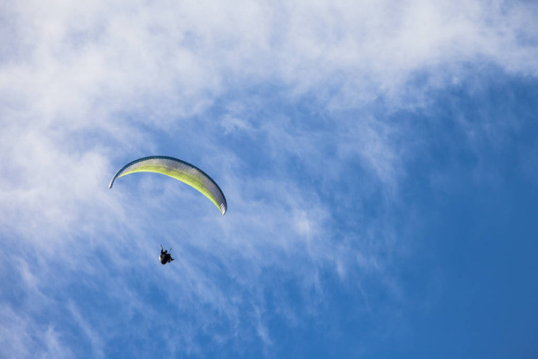 a man paragliding solo on the blue sky over the Dolomites in Italy in a sunny day - 写真・画像