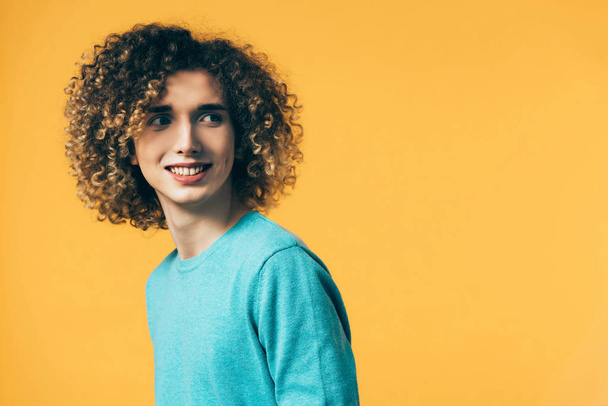 smiling curly teenager looking away isolated on yellow - Fotografie, Obrázek