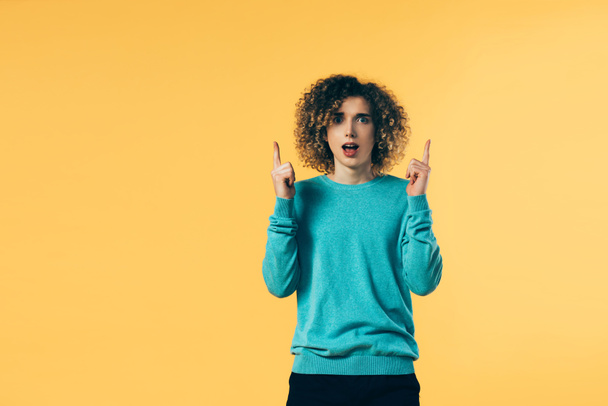 shocked curly teenager pointing with fingers isolated on yellow - Фото, изображение