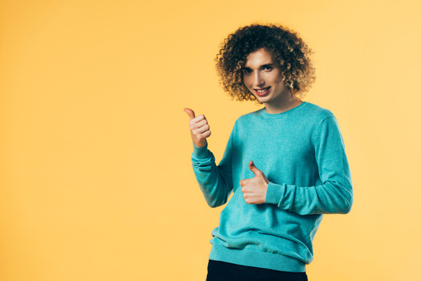 boldog göndör tinédzser mutatja hüvelykujját elszigetelt sárga - Fotó, kép