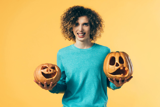 rizado adolescente celebración de Halloween calabazas aislado en amarillo
 - Foto, Imagen