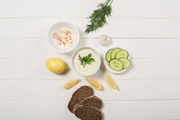 Top view of tzatziki sauce with ingredients on white wooden background - Photo, Image