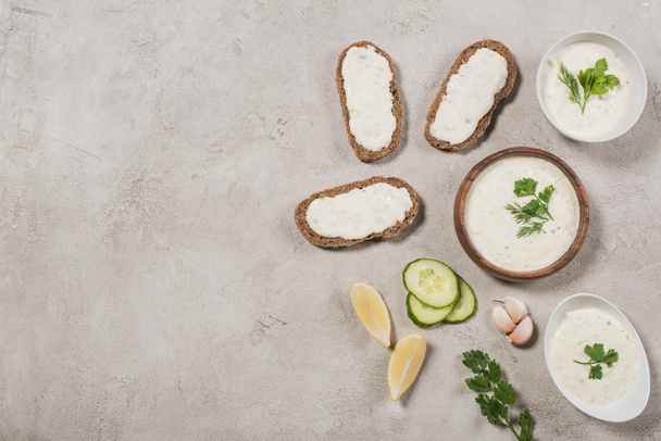 Top view of homemade tzatziki sauce with bread and ingredients on stone background - Photo, Image