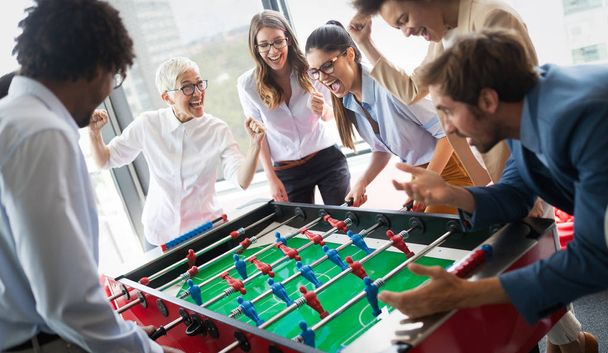 Business people having great time together.Colleagues playing table football in modern office. - Foto, afbeelding