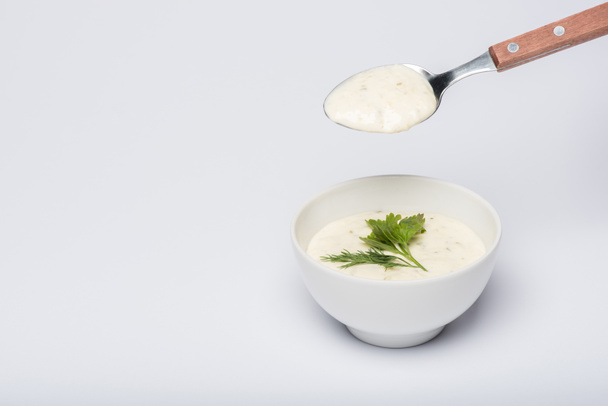 Tasty tzatziki sauce with greenery and spoon on white background - Photo, Image