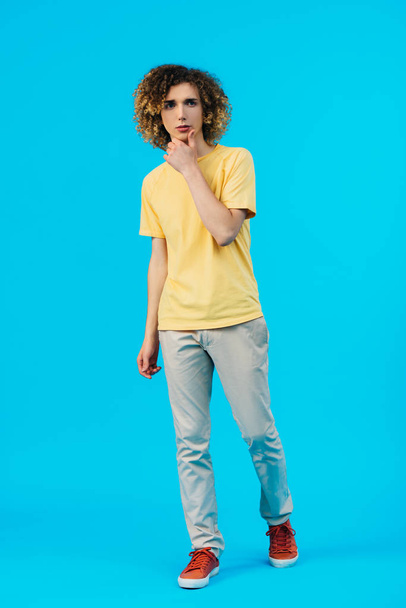 pensive curly teenager looking away isolated on blue - Foto, Imagen