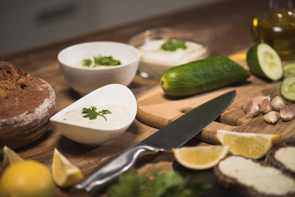 Selektywne skupienie pysznego sosu tzatziki z surowcami na stole kuchennym  - Zdjęcie, obraz