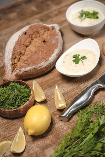 hausgemachte Tzatziki-Sauce mit Brot und rohen Zutaten auf Holztisch  - Foto, Bild