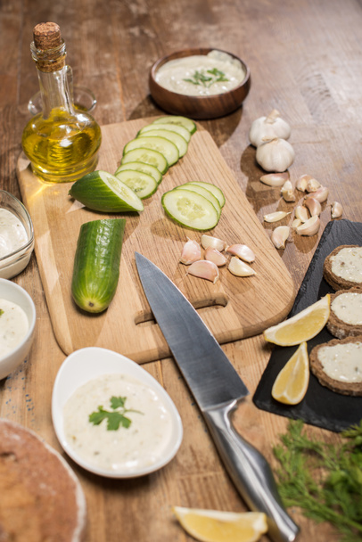 Tzatziki sauce with fresh ingredients and bread on wooden table - Fotó, kép