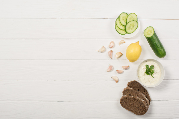 Вид зверху соусу з органічними інгредієнтами та хлібом на білому дерев'яному фоні
 - Фото, зображення