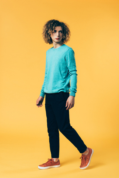 curly teenager walking on yellow background - Foto, Imagen