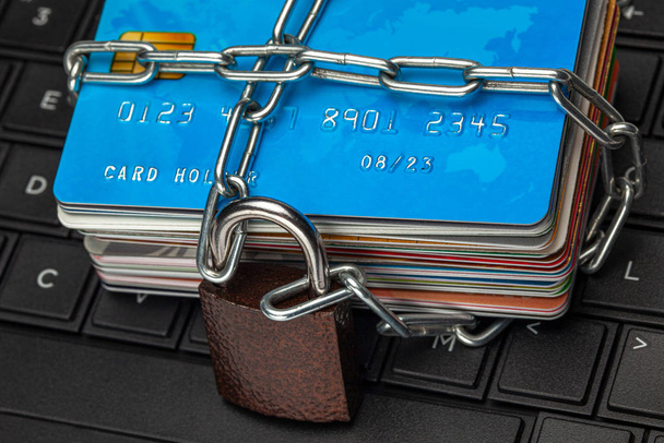 Closed access to credit cards, blocked, lock. A stack of credit cards and a padlock with a chain on a laptop keyboard - Photo, Image