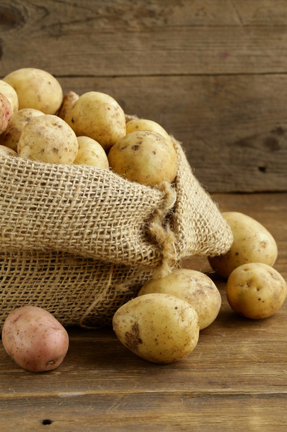 Fresh organic potatoes on a wooden background, rustic style - Foto, afbeelding
