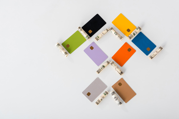 flat lay with multicolored credit card templates near cash rolls on white  - Foto, immagini