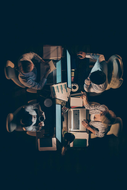 Vertical top above high angle view of four smart clever businesspeians It experts executive managers solving tech issue typing e-mail keyboard at late night work place station - Fotografie, Obrázek