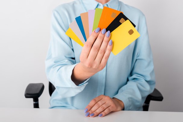 vista cortada da mulher segurando modelos de cartão de crédito multicoloridos isolados no branco
  - Foto, Imagem
