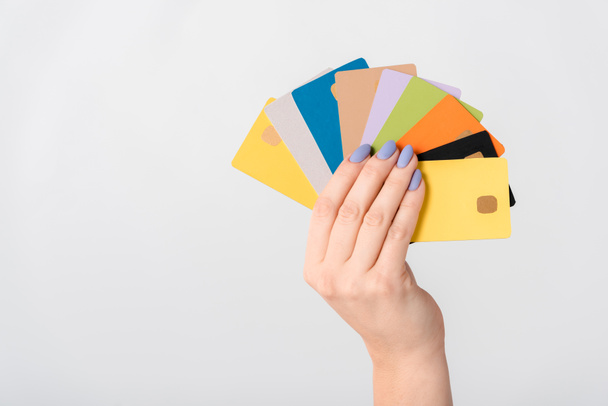 cropped view of woman holding multicolored credit card templates in hand isolated on white  - Fotó, kép