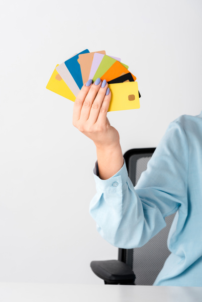vista recortada de la mujer sosteniendo plantillas de tarjetas de crédito multicolores en la mano aisladas en blanco
  - Foto, imagen