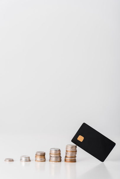 pile di monete d'argento e d'oro vicino modello di carta di credito nera su bianco
  - Foto, immagini