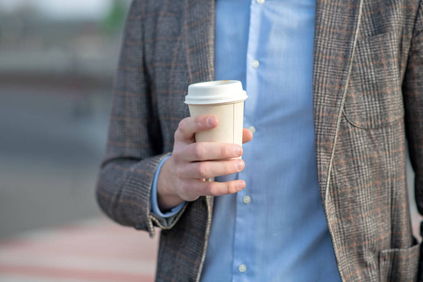 Man in a blue shirt holding a cup of coffee - Fotó, kép