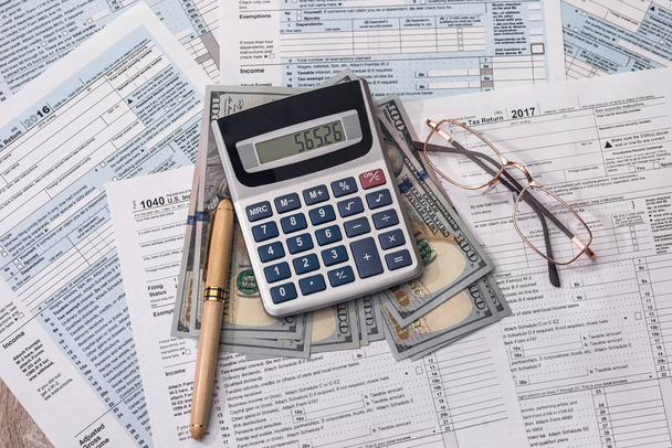 Formulário fiscal com dólar, calculadora e caneta
 - Foto, Imagem