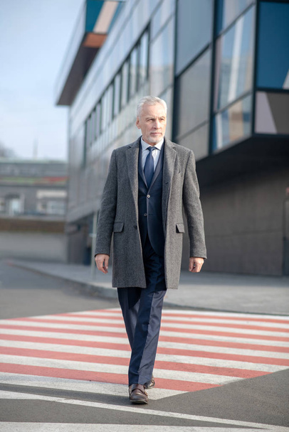 Mature man in elegant coat crossing the street - Фото, зображення