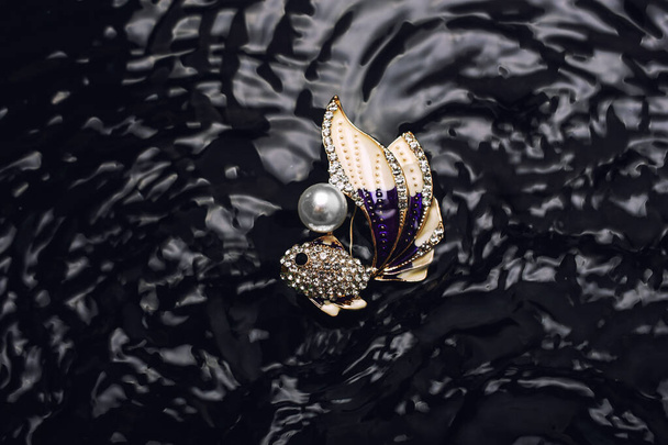 kultainen emaloitu rintaneula kala timantteja ja helmi vedessä
 - Valokuva, kuva