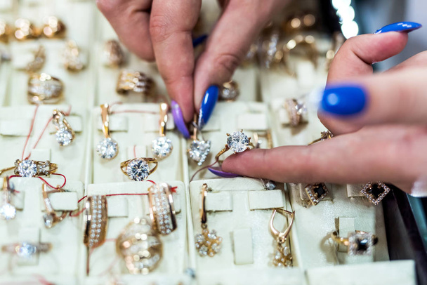 A női kezek arany ékszereket mutatnak a boltban - Fotó, kép