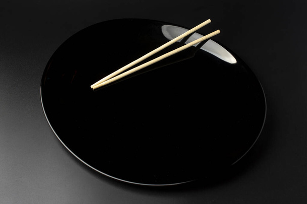 czarny pusty talerz z chińskimi pałeczkami - Zdjęcie, obraz