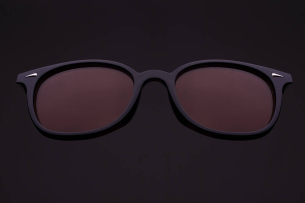 Siyah üzerine plastik kenarlı retro güneş gözlüğü. - Fotoğraf, Görsel