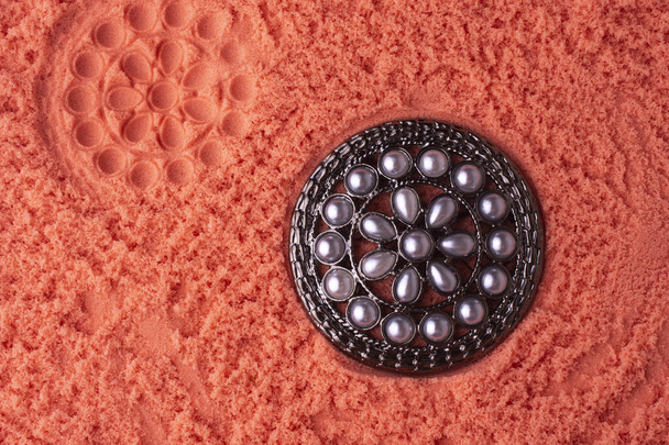 broche ronde avec perles sur le sable rose
 - Photo, image