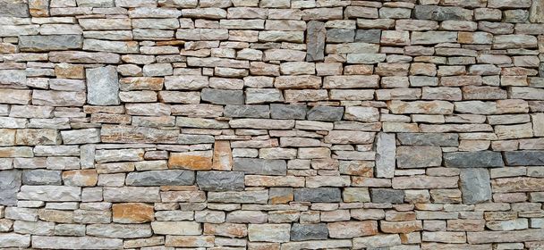 Δροσερός και σύγχρονος τεράστιος τοίχος ταπετσαρίας φτιαγμένος από φυσικά υλικά όπως πέτρα και πέτρες που φτιάχνουν έναν τοίχο από τούβλα με άνισα τούβλα - Φωτογραφία, εικόνα