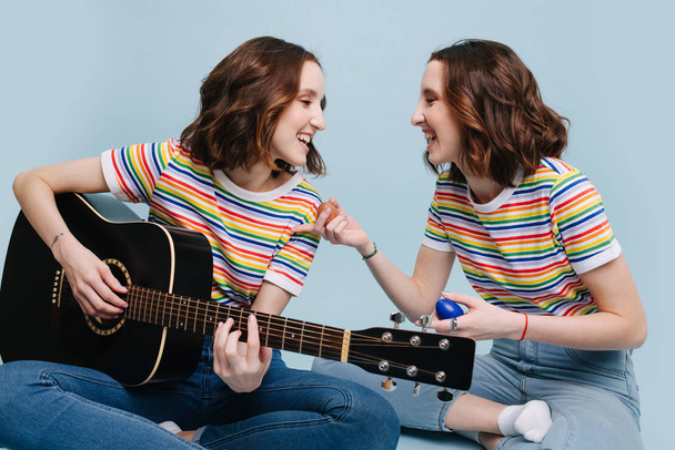 Two twin sisters sing and play on guitar and percussion together - Fotó, kép
