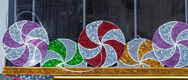 Новогодний фасад дома украшен рождественскими белыми и красными гирляндами и мишурой
 - Фото, изображение