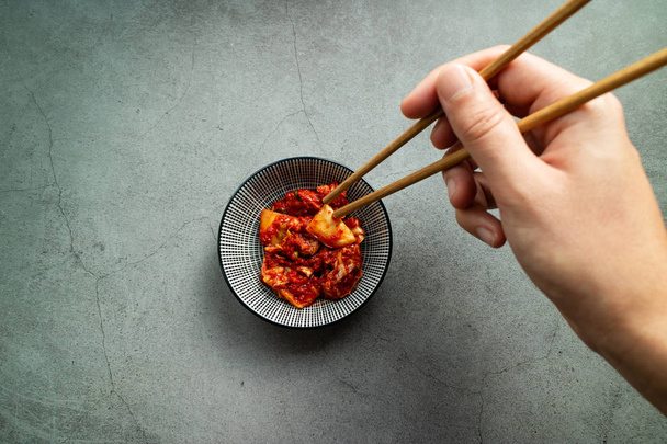 Caucasian man's hand using chopsticks to take Kimchi. Korean cui - Photo, Image