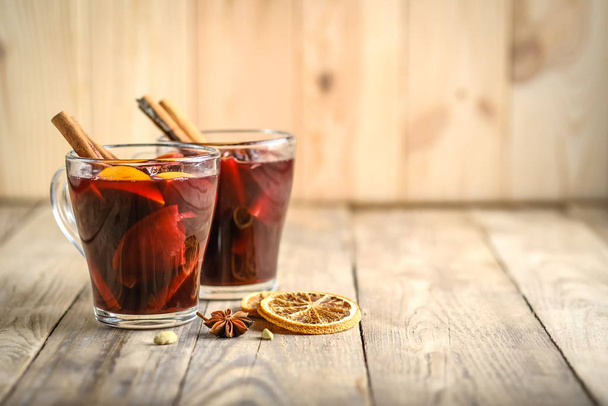 Mulled wine in glasses with apples, orange, cinnamon and star anise. Hot Christmas drink on a rustic background with copy space. - Fotó, kép