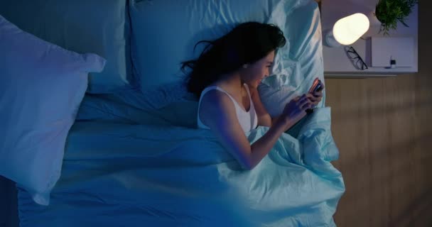 woman use smartphone on bed - Кадри, відео